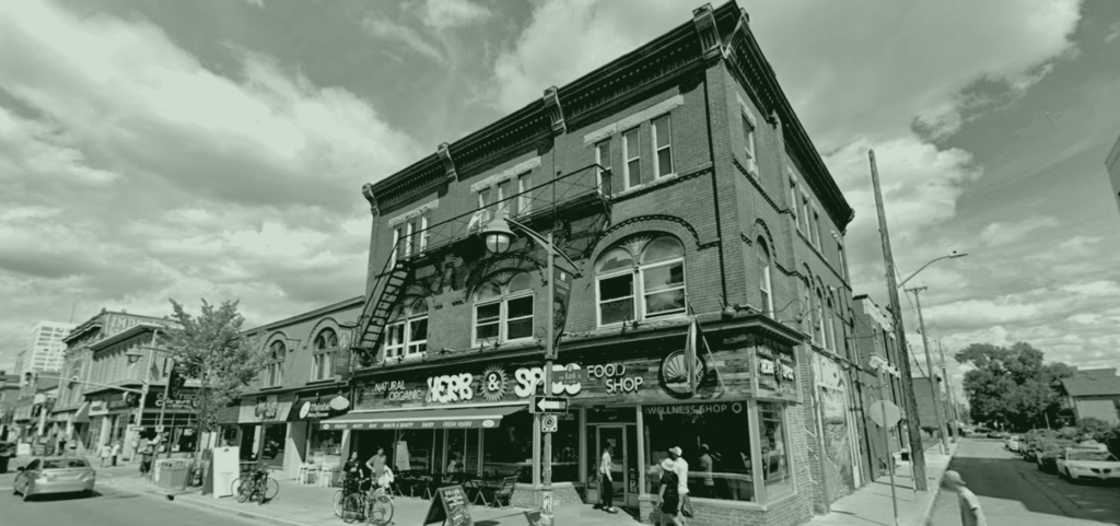 An image of the Herb & Spice storefront in Ottawa - a brick building with a fire escape, and a sign that reads "Herb & Spice - Natural Organic Food Shop". The image is black and white with a green tint.