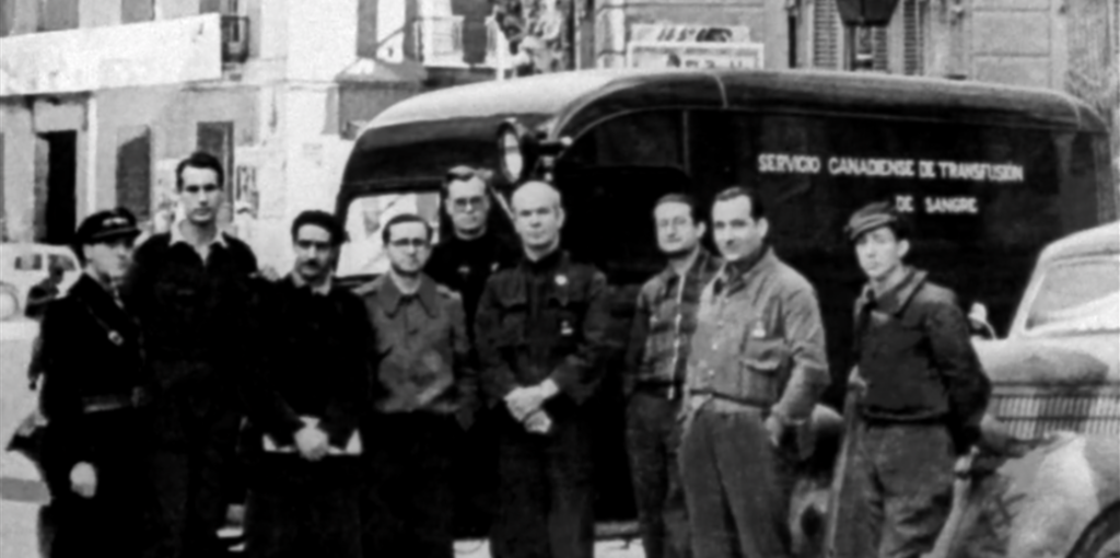 Norman Bethune and other medical volunteers stand in front of a mobile blood transfusion unit in Spain, 1936.