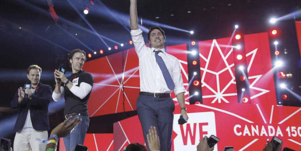 Justin Trudeau walks off stage at a WE charity event, waving to the crowd